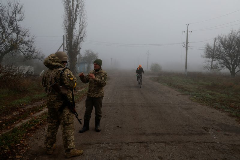 &copy; Reuters. A Ukrainian serviceman speaks with a chaplain while a local resident rides a bicycle along a street, amid Russia’s attack on Ukraine, in a village near the newly recaptured city of Snihurivka, in Mykolaiv region, Ukraine November 10, 2022.  REUTERS/Vale