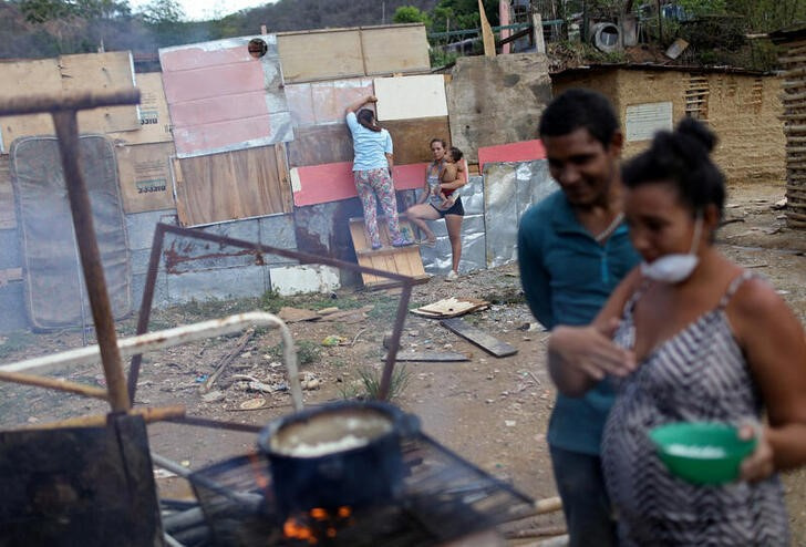 &copy; Reuters. Imagen de archivo de una familia cocinando junto a una vivienda precaria en una parcela ocupada en la municipalidad de Sucre, cerca de Caracas, Venezuela. 12 junio 2020. REUTERS/Manaure Quintero