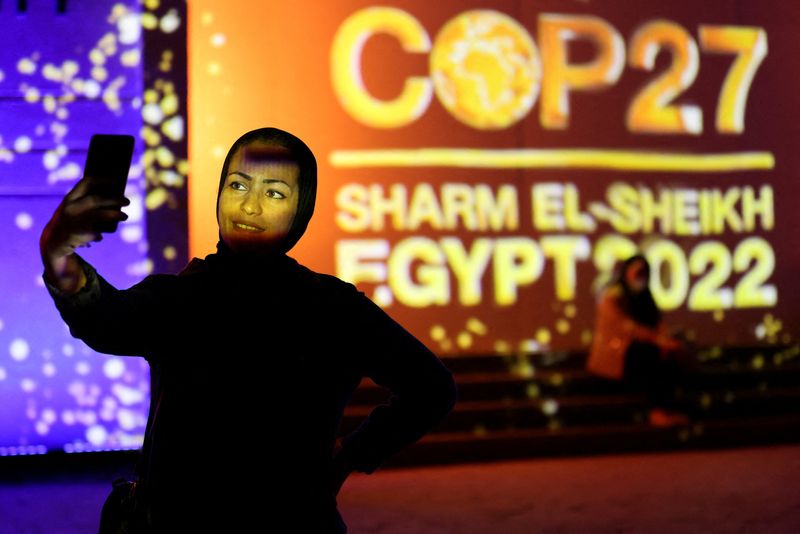 &copy; Reuters. FILE PHOTO: A woman takes a selfie in front of a wall lit with the sign of COP27, as the COP27 climate summit takes place, at the Green Zone in Sharm el-Sheikh, Egypt November 10, 2022. REUTERS/Mohamed Abd El Ghany/File Photo