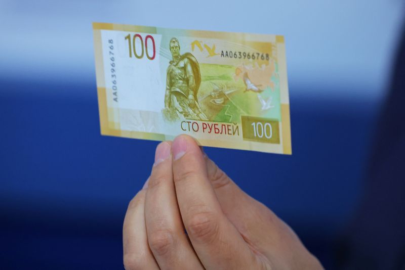 © Reuters. FILE PHOTO: Deputy Governor of the Bank of Russia Sergey Belov holds the newly designed Russian 100-rouble banknote during a presentation in Moscow, Russia June 30, 2022. REUTERS/Evgenia Novozhenina