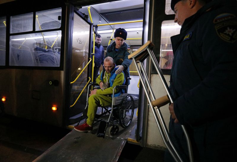 © Reuters. أفراد من وزارة الطوارئ الروسية يساعدون شخصا على كرسي متحرك تم إجلاؤه من الجزء الذي تسيطر عليه روسيا من منطقة خيرسون الأوكرانية إلى بلدة بشبه جزيرة القرم يوم الخميس. تصوير: ألكسي بافليشاك - رويترز.