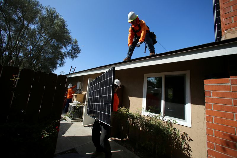 © Reuters. FILE PHOTO: Workers lift a solar panel onto a roof during a residential solar installation in Scripps Ranch, San Diego, California, U.S. October 14, 2016. Picture taken October 14, 2016. REUTERS/Mike Blake/File Photo