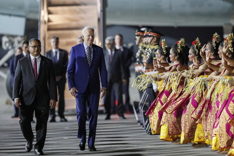 © Reuters. U.S. President Joe Biden walks as Balinese dancers perform during his arrival for the G20 Summit at Ngurah Rai International airport in Bali, Indonesia, 13 November 2022. Made Nagi/Pool via REUTERS