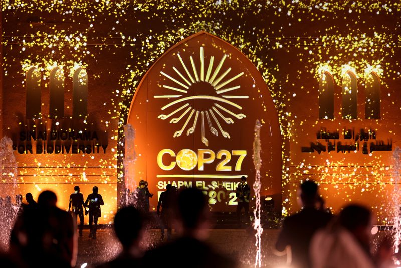 &copy; Reuters. People pass in front of a wall lit with the sign of COP27 as the COP27 climate summit takes place, at the Green Zone in Sharm el-Sheikh, Egypt November 10, 2022. REUTERS/Mohamed Abd El Ghany