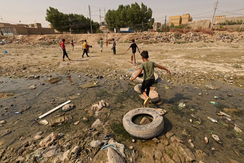 &copy; Reuters. أطفال يلعبون الكرة على مجرى نهر المشخاب الجاف في مدينة نجف بالعراق يوم العاشر من أكتوبر تشرين الأول 2022. تصوير: علاء المرجاني - رويترز. 