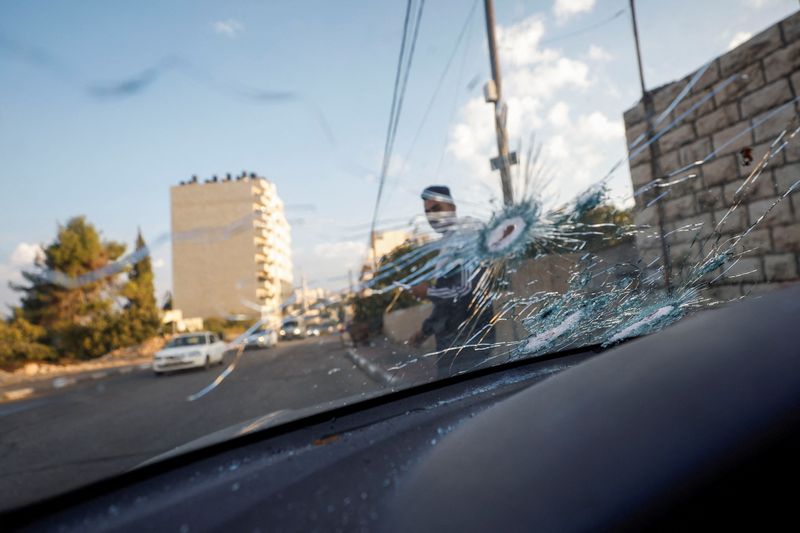 © Reuters. فلسطيني يمر بجانب السيارة المتضررة بالقرب من رام الله يوم الاثنين. تصوير: محمد تركمان - رويترز.


