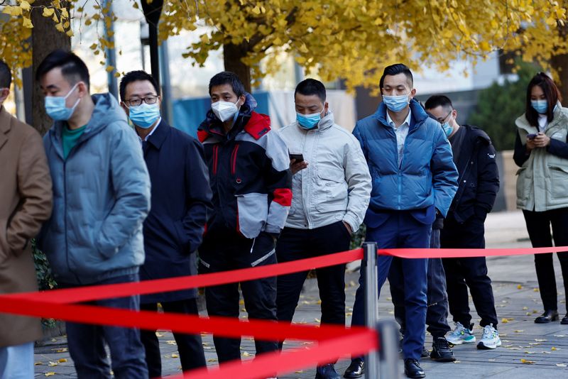 &copy; Reuters. Gente hace cola para someterse a una prueba de ácido nucleico para la enfermedad del coronavirus (COVID-19) en un puesto de pruebas cerca de un edificio de oficinas en el Distrito Central de Negocios, en el distrito de Chaoyang, Pekín, China. 15 de novi