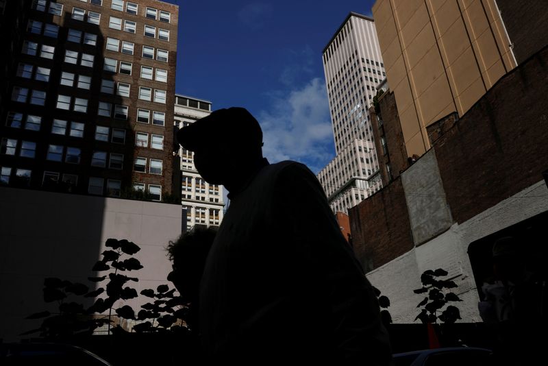 &copy; Reuters. FILE PHOTO: A man is seen silhouetted wearing a protective face mask walking near the financial district of New York City, U.S., October 18, 2021. REUTERS/Shannon Stapleton