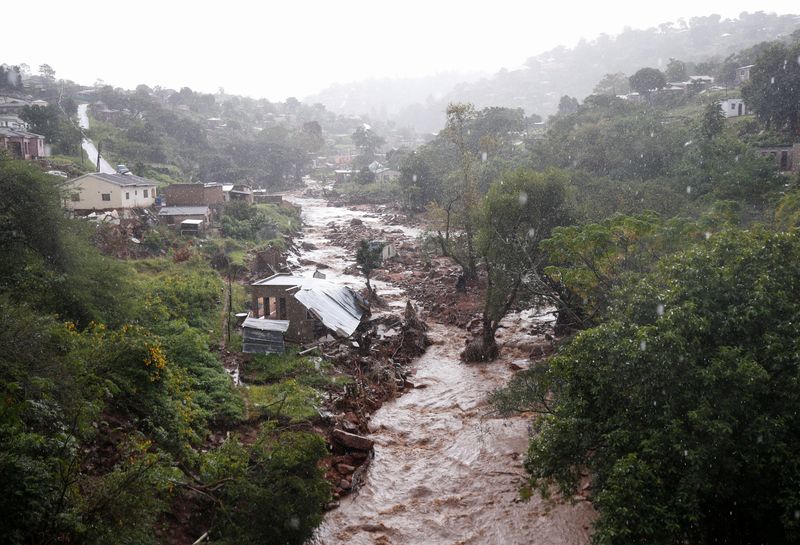 © Reuters. A river runs high after heavy rains, next to homes which were damaged during previous flooding, in kwaNdengezi near Durban, South Africa, May 22, 2022. REUTERS/Rogan Ward