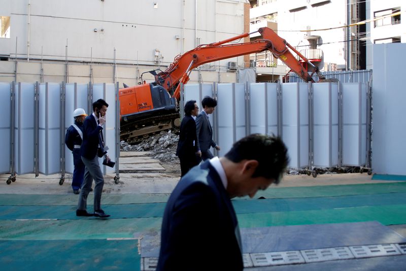 © Reuters. FILE PHOTO: Businessmen walk past heavy machinery at a construction site in Tokyo's business district, Japan, January 16, 2017.    REUTERS/Toru Hanai