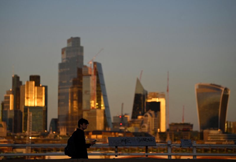 &copy; Reuters. FILE PHOTO: A man crosses Waterloo Bridge during the evening rush-hour with skyscrapers of the City of London financial district seen behind in London, Britain, October 10, 2022.  REUTERS/Toby Melville/File Photo