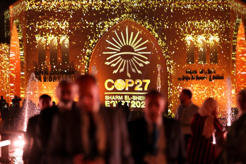 &copy; Reuters. FILE PHOTO: People pass in front of a wall lit with the sign of COP27 as the COP27 climate summit takes place, at the Green Zone in Sharm el-Sheikh, Egypt November 10, 2022. REUTERS/Mohamed Abd El Ghany