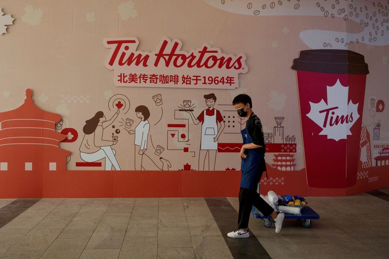 &copy; Reuters. Homem passa por um cartaz na frente de uma loja anunciando a abertura de um café da rede canadense Tim Hortons, em Pequim, China. 06/07/2020. REUTERS/Thomas Peter/File Photo