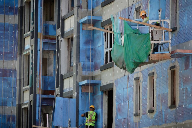 © Reuters. Men work at a construction site of apartment buildings in Beijing, China, July 15, 2022. REUTERS/Thomas Peter