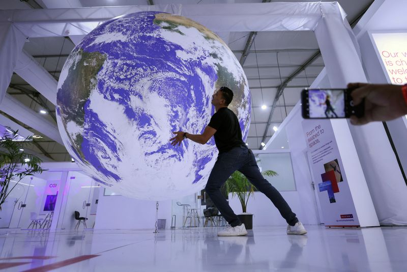 &copy; Reuters. An attendee poses for a picture near a model earth during the COP27 climate summit in Sharm el-Sheikh, Egypt November 19, 2022. REUTERS/Mohamed Abd El Ghany