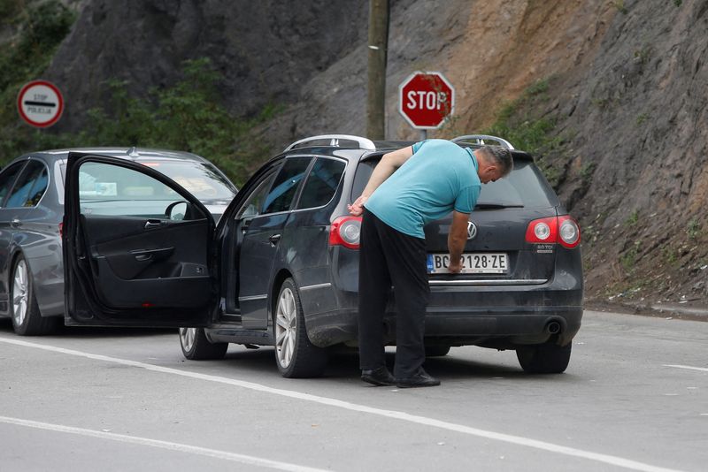 &copy; Reuters. FOTO DE ARCHIVO: Un conductor retira una pegatina que cubre las marcas nacionales de la matrícula de su coche en el paso fronterizo de Jarinje, Kosovo. 1 de septiembre, 2022. REUTERS/Ognen Teofilovski/Archivo