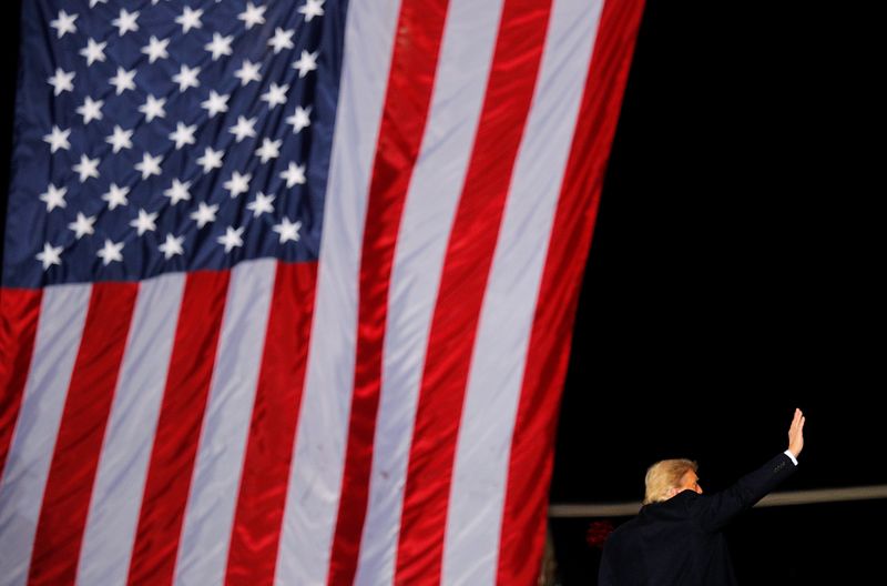 © Reuters. FILE PHOTO: U.S. President Donald Trump gestures next to a U.S. flag while campaigning for Republican Senator Kelly Loeffler on the eve of the run-off election to decide both of Georgia's Senate seats, in Dalton, Georgia, U.S., January 4, 2021. REUTERS/Brian Snyder