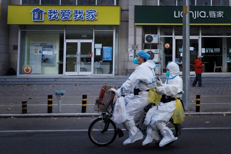 &copy; Reuters. Personale di prevenzione della pandemia in tuta protettiva su una bicicletta elettrica, mentre continuano i focolai di coronavirus (COVID-19) a Pechino, 21 novembre 2022. REUTERS/Thomas Peter