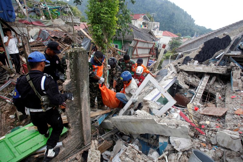 © Reuters. Rescuers carry a body bag with a victim through the rubble of collapsed buildings during a rescue operation after earthquake hit in Cianjur, West Java province, Indonesia, November 22, 2022, in this photo taken by Antara Foto. Antara Foto/Yulius Satria Wijaya/ via REUTERS