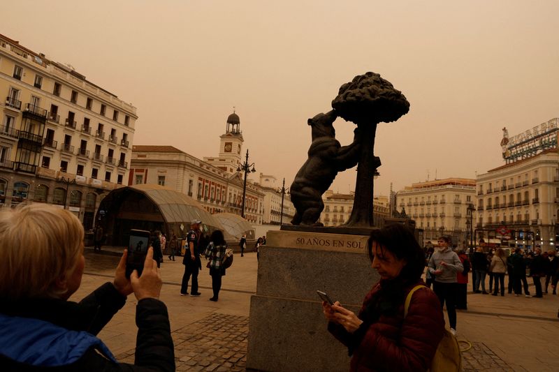 &copy; Reuters. FILE PHOTO: Tourists take pictures of Puerta del Sol square as storm Celia blew sand from the Sahara desert over Madrid, Spain, March 15, 2022. REUTERS/Susana Vera