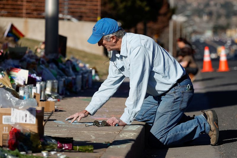 © Reuters. Peter Aubrey of Colorado Springs writes a note with chalk on the sidewalk at a memorial site for victims after the mass shooting at LGBTQ nightclub Club Q in Colorado Springs, Colorado, U.S. November 22, 2022.  REUTERS/Isaiah J. Downing