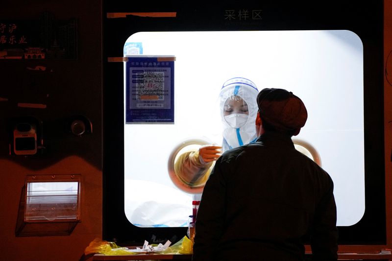&copy; Reuters. عامل بقطاع الصحة يرتدي سترة واقية يأخذ مسحة من رجل لإجراء اختبار الإصابة بفيروس كورونا في أحد المراكز بشنغهاي يوم 18 نوفمبر تشرين الثاني 2022. 