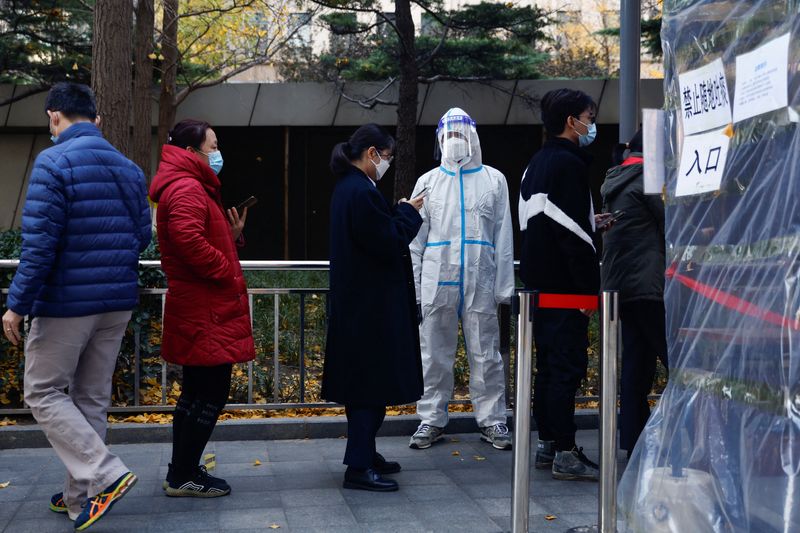 &copy; Reuters. 　中国の新型コロナウイルス感染拡大を受け、アナリストの間で年末の同国の石油需要見通しを下方修正する動きが出ている。写真は新型コロナの検査を受けるために行列する人々。北京で