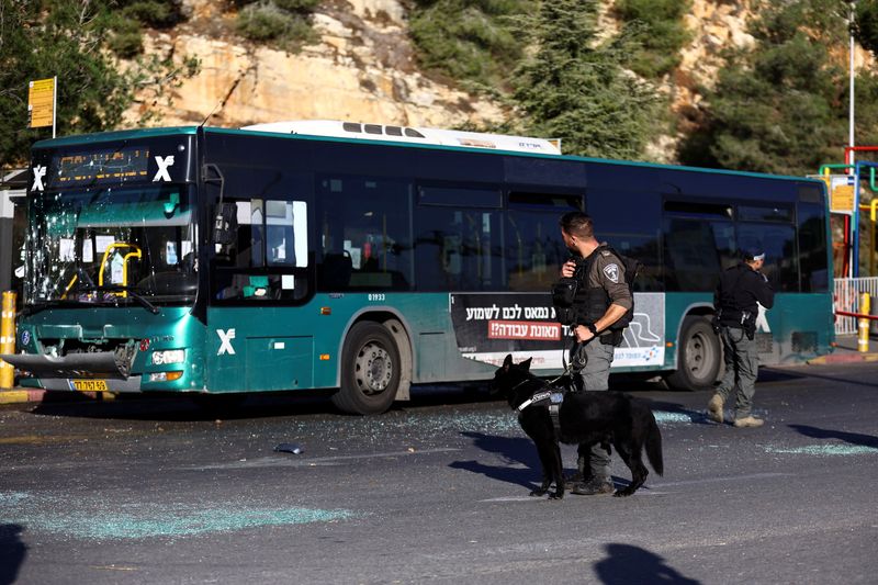 &copy; Reuters. شرطي يمسك كلبا بجوار حافلة تضررت في أعقاب انفجار قرب محطة حافلات في القدس يوم الأربعاء. تصوير: رونين زفولون - رويترز