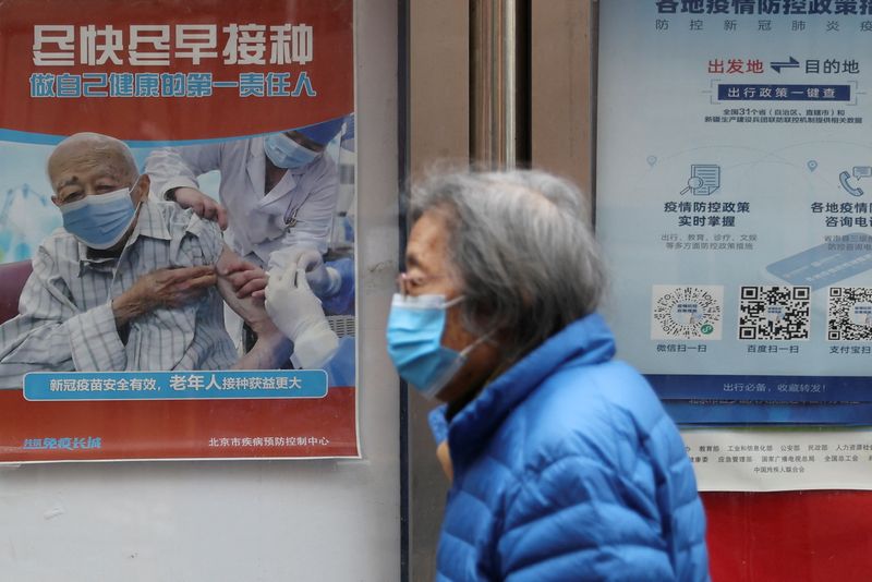 &copy; Reuters. FILE PHOTO: A person walks past a poster encouraging elderly people to get vaccinated against the coronavirus disease (COVID-19), near a residential compound in Beijing, China March 30, 2022. REUTERS/Tingshu Wang