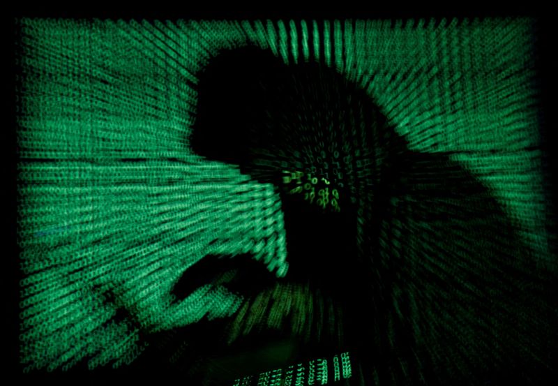 &copy; Reuters. Photo d'illustration d'un homme avec un ordinateur portable sur un fond affichant du code informatique. /Photo prise le 13 mai 2017/REUTERS/Kacper Pempel