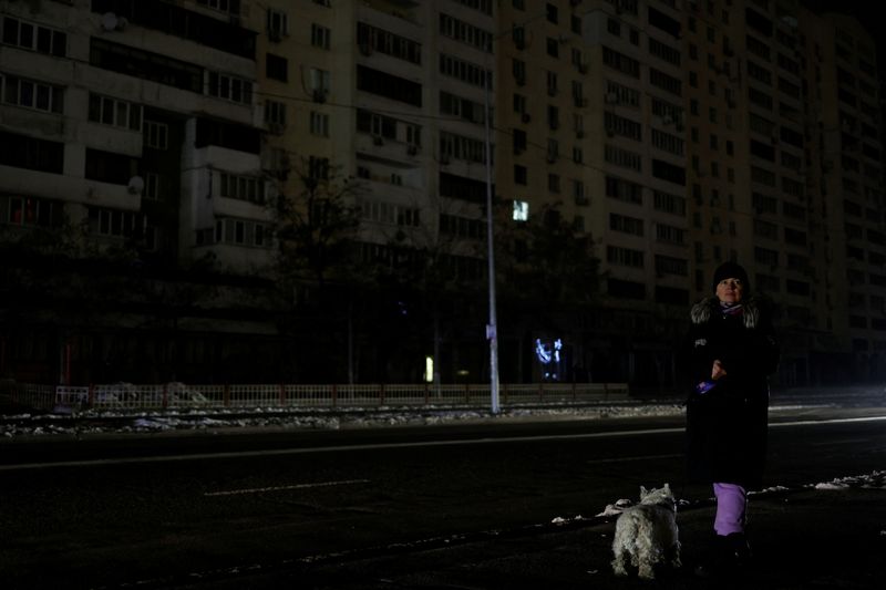 &copy; Reuters. Una mujer con un perro espera un autobús en una calle sin electricidad después de que la infraestructura civil crítica fuera alcanzada por los ataques de misiles rusos, en medio de la invasión rusa de Ucrania, en Kiev, Ucrania. 23 de noviembre de 2022