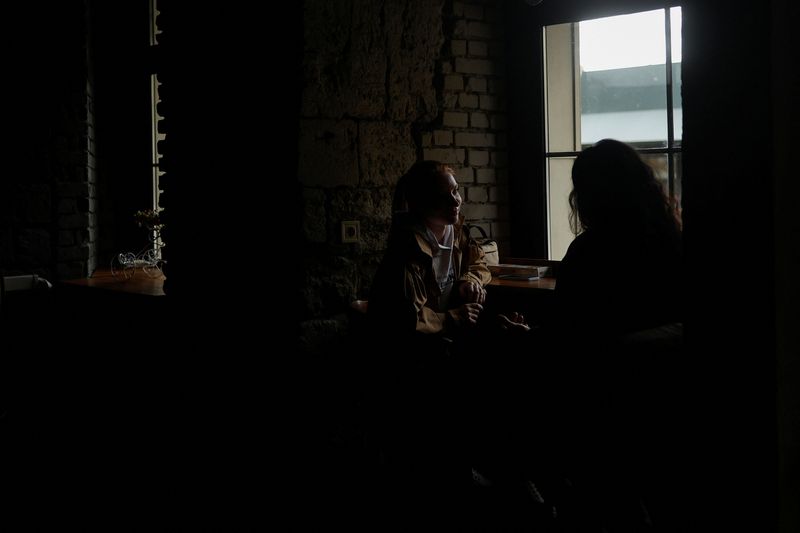 &copy; Reuters. امرأتان تتبادلان أطراف الحديث في مقهى مظلم بسبب انقطاع التيار الكهربي إثر هجمات صاروخية روسية على ميكوليف بأوكرانيا يوم 22 أكتوبر تشرين الأ