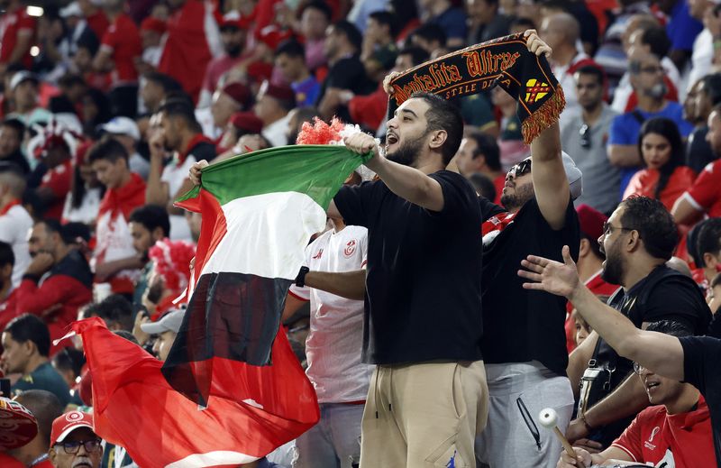 © Reuters. مشجع يحمل علم فلسطيني في استاد مباراة الدنمرك أمام تونس بكأس العالم لكرة القدم في قطر يوم 22 نوفمبر تشرين الثاني 2022. تصوير: صهيب سالم - رويترز. 