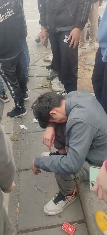 &copy; Reuters. FOTO DE ARCHIVO: Una persona herida se sienta en el suelo durante una protesta frente a la fábrica del proveedor de Apple, Foxconn, en Zhengzhou, China, el 23 de noviembre de 2022, en esta imagen fija obtenida por REUTERS de un vídeo. 