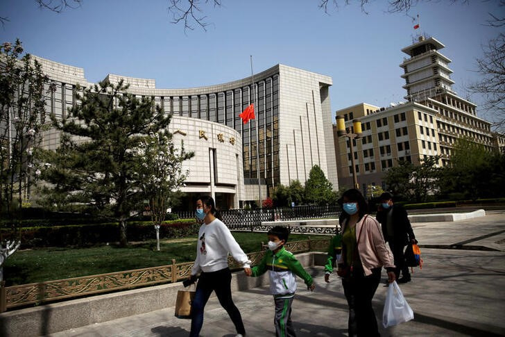 &copy; Reuters. Imagen de archivo de personas con mascarillas pasando frente a la sede del Banco Popular de China en Pekín, China.