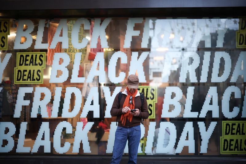 © Reuters. A person stands in front of Black Friday signage in shop windows during Black Friday on Oxford Street in London, Britain, November 25, 2022. REUTERS/Henry Nicholls