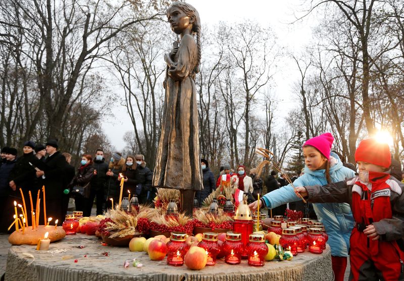 © Reuters. FILE PHOTO: Children place ears of wheat as they visit a monument to Holodomor victims during a commemoration ceremony marking the 87th anniversary of the famine of 1932-33, in which millions died of hunger, in Kyiv, Ukraine November 28, 2020.  REUTERS/Valentyn Ogirenko/File Photo