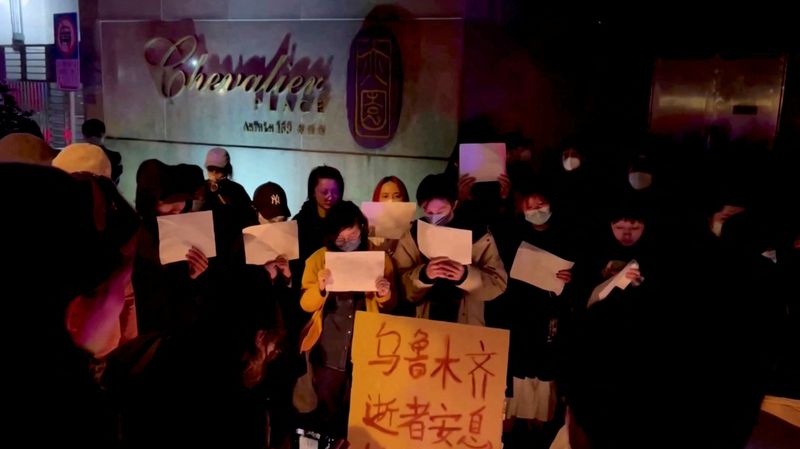 &copy; Reuters. أشخاص يحملون لافتات خلال وقفة احتجاج على ضحايا حريق وقع في مبنى شاهق في أورومتشي عاصمة منطقة شينجيانغ، في شنغهاي يوم السبت في صورة حصلت عليه