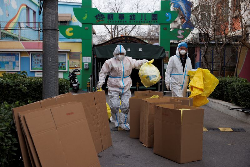 &copy; Reuters. العاملون في مجال الوقاية من الأوبئة يلقون مخلفات طبية في سلال القمامة داخل مجمع سكني بالعاصمة الصينية بكين يوم الأحد لمواجهة تفشي فيروس كور