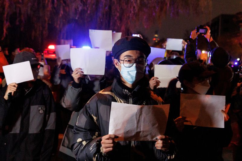 &copy; Reuters. 　中国の新型コロナウイルス規制に対する抗議活動で各地の参加者は無言で白い紙を掲げ、抵抗の意を表している。２７日に北京で撮影（２０２２年　ロイター/Thomas Peter）