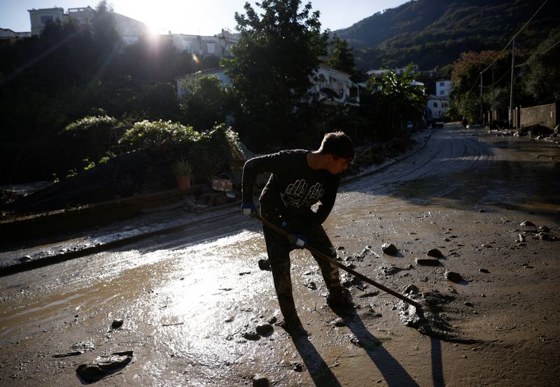 &copy; Reuters. Une personne nettoie une rue couverte de boue, suite à un glissement de terrain sur l'île italienne d'Ischia. /Photo prise le 28 novembre 2022/REUTERS/Guglielmo Mangiapane
