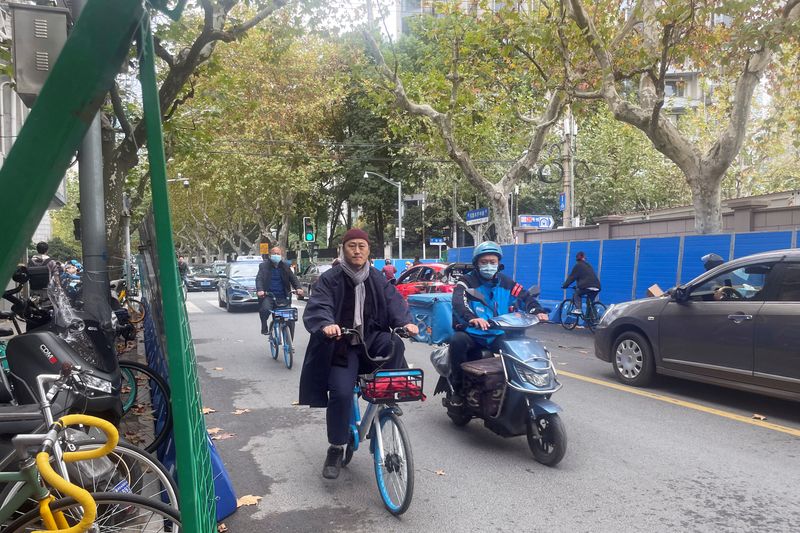&copy; Reuters. La gente pasa por las barreras instaladas a lo largo de la vía Wulumuqi, donde se llevaron a cabo protestas contra las medidas para enfrentar la enfermedad del coronavirus (COVID-19) tras el mortal incendio de Urumqi, en Shanghái, China, el 28 de noviem