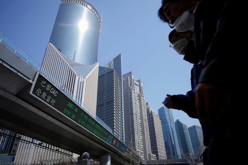 © Reuters. Pedestrians wearing face masks walk near an overpass with an electronic board showing stock information, following an outbreak of the coronavirus disease (COVID-19), at Lujiazui financial district in Shanghai, China March 17, 2020. REUTERS/Aly Song/File Photo