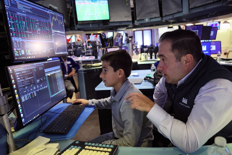 © Reuters. FILE PHOTO: A specialist trader works with his son during a traditional bring-your-kids-to-work day on the floor at the New York Stock Exchange (NYSE) in New York City, U.S., November 25, 2022. REUTERS/Brendan McDermid