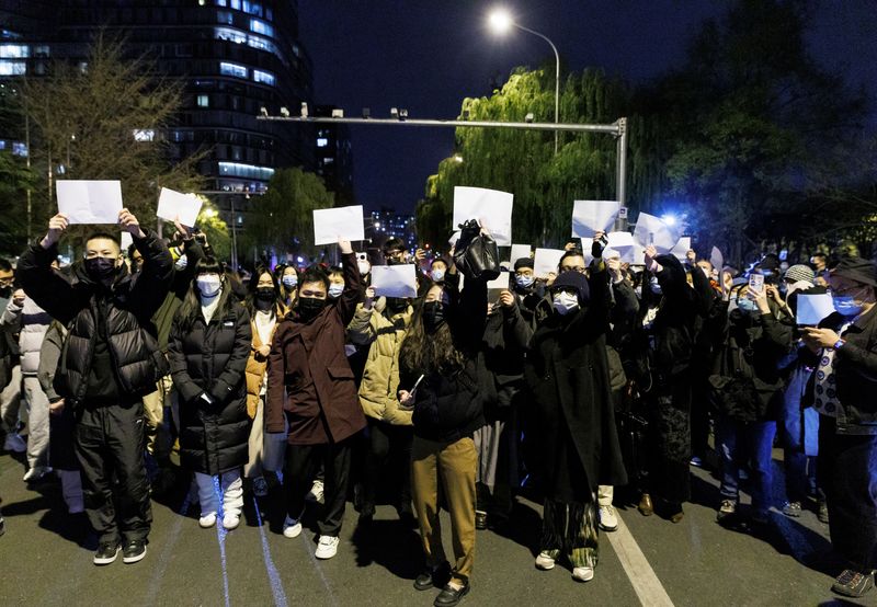 © Reuters. FILE PHOTO: People gather for a vigil and hold white sheets of paper in protest over coronavirus disease (COVID-19) restrictions, during a commemoration of the victims of a fire in Urumqi, as outbreaks of COVID-19 continue, in Beijing, China, November 27, 2022. REUTERS/Thomas Peter/File Photo