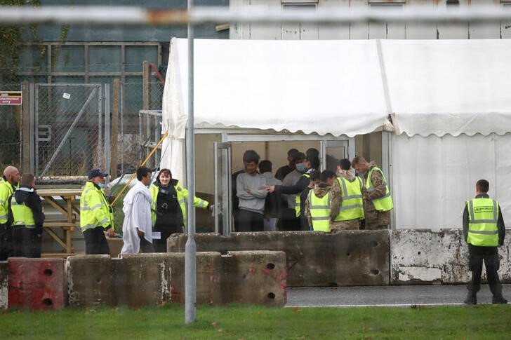 © Reuters. FILE PHOTO: People wait to board a bus at the migrant processing centre in Manston, Britain, November 7, 2022. REUTERS/Henry Nicholls