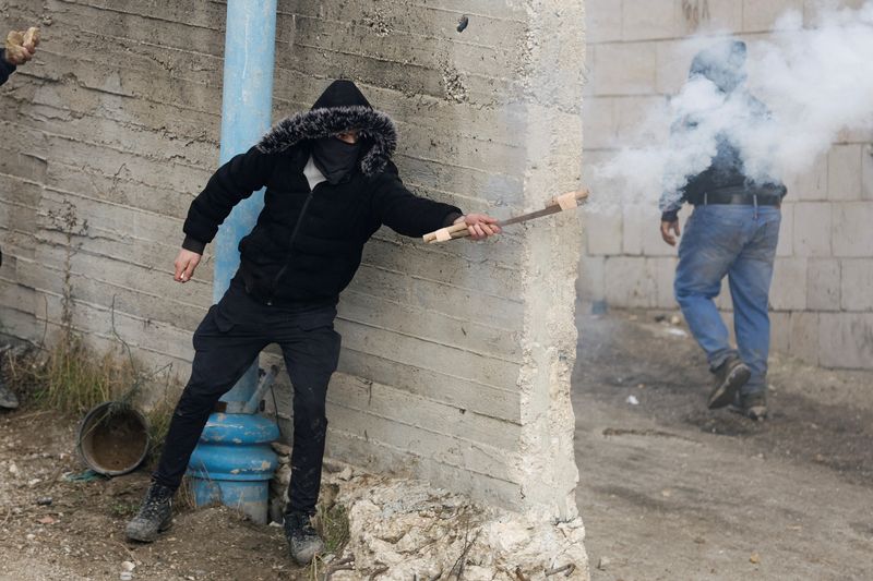 &copy; Reuters. Un manifestant palestinien lâche un pétard lors d'affrontements avec les forces israéliennes, près d'Hébron, en Cisjordanie occupée par Israël. /Photo prise le 29 novembre 2022/REUTERS/Mussa Qawasma
