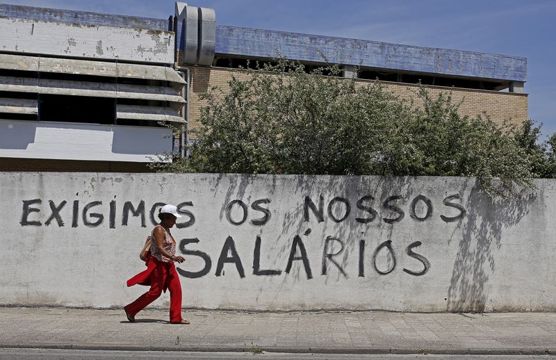 &copy; Reuters. FILE PHOTO: A woman walks past a wall with graffiti saying "We demand our wages" in Alhos Vedros, Portugal, May 11, 2015. To match PORTUGAL-UNEMPLOYMENT/ REUTERS/Hugo Correia