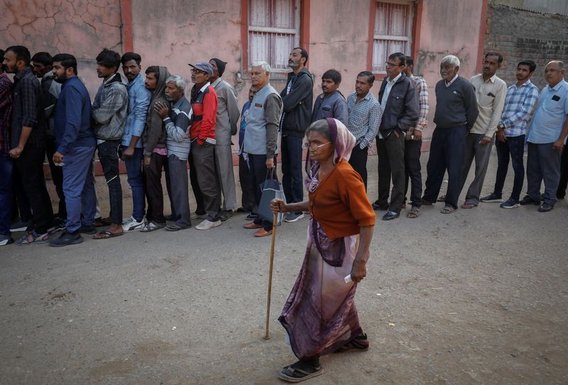 © Reuters. A woman arrives as others wait in a queue to cast their vote during the first phase of state assembly election in Limbdi town of Surendranagar district in the western state of Gujarat, India, December 1, 2022. REUTERS/Amit Dave