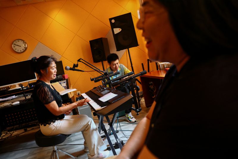 &copy; Reuters. Zhao Guorong, 59, plays the keyboard as she performs with her son Zu Wenbao, 23, and Tian Yi, 44, during a practice session of the band formed by the mothers of Star Kids, called Mums of Star Kids, at the music studio of 38-year-old teacher Chen Shensi in
